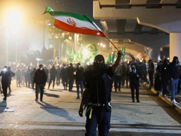 Seorang demonstran pendukung kelompok bersenjata Irak melambaikan bendera Iran dalam aksi protes di Baghdad (dok. Reuters)