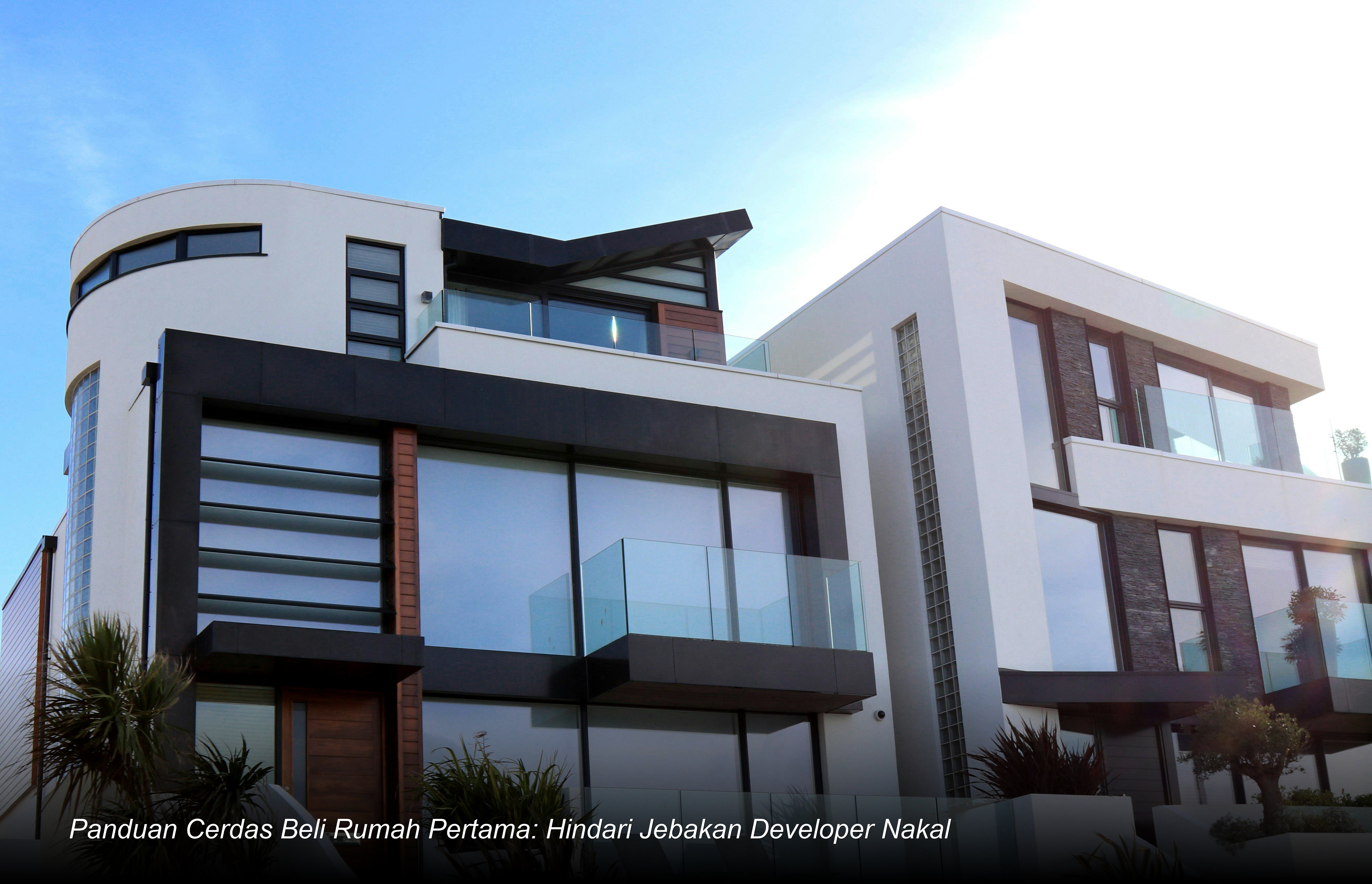 Seorang pasangan muda sedang menandatangani dokumen akad kredit di meja bank dengan latar belakang maket perumahan modern.