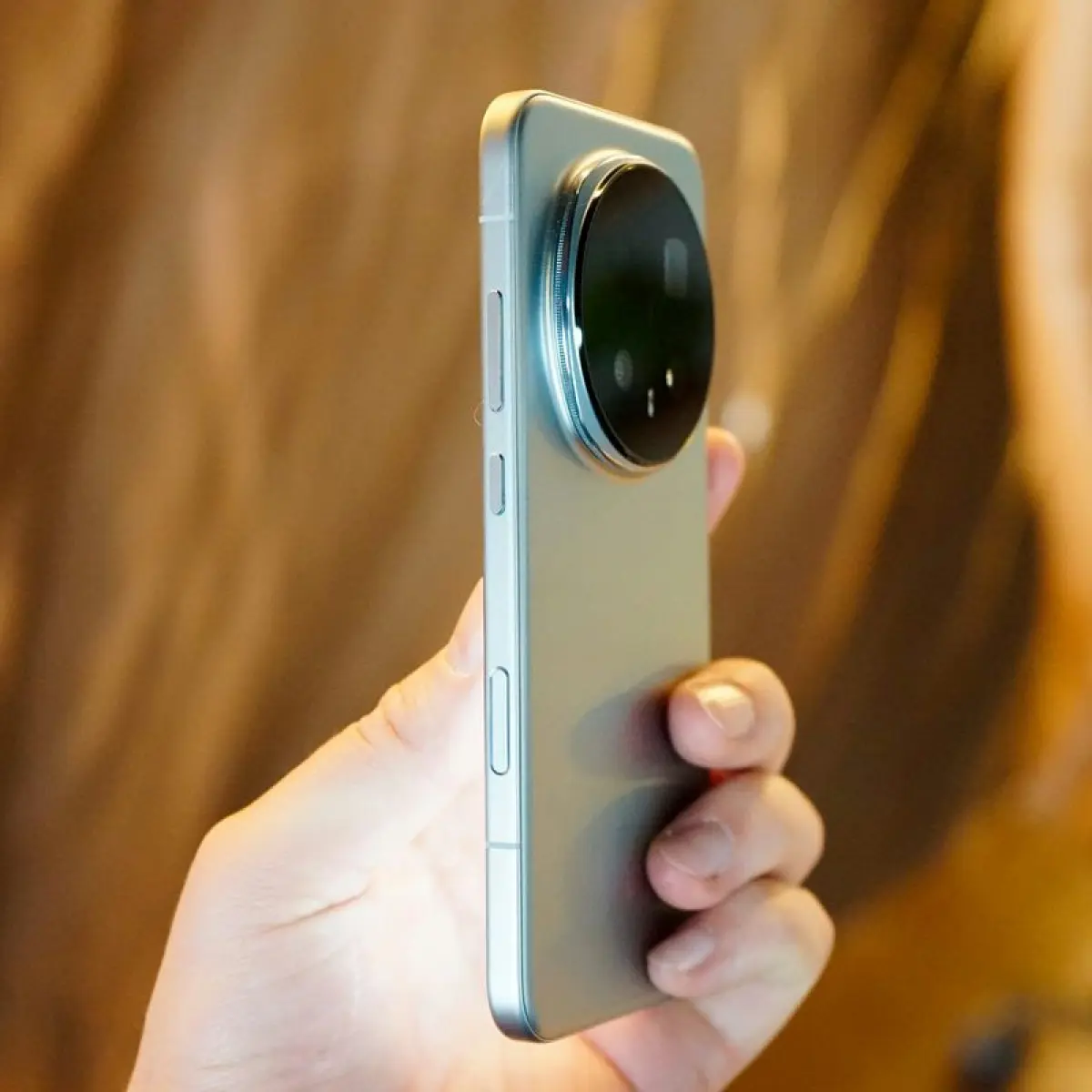 close-up tangan memegang smartphone lensa kamera besar (Foto: Unsplash)