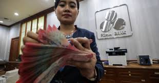 Karyawati menghitung uang di salah satu kantor cabang Bank Panin di Jakarta, Senin (5/5/2025). Bisnis/Arief Hermawan P