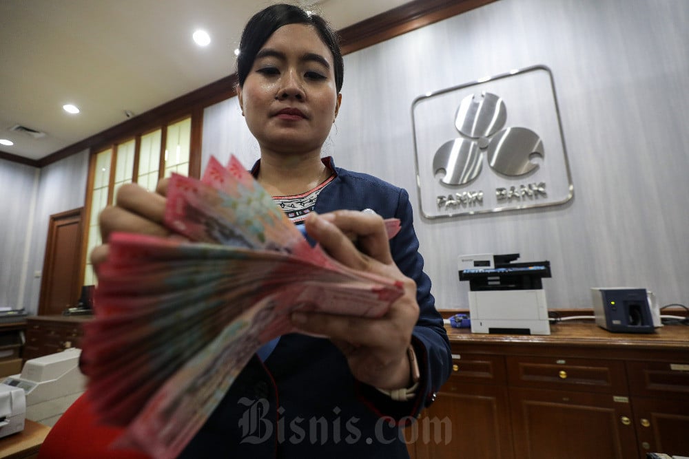 Karyawati menghitung uang di salah satu kantor cabang Bank Panin di Jakarta, Senin (5/5/2025). Bisnis/Arief Hermawan P