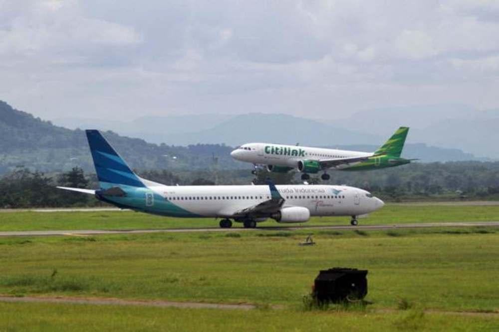 Ilustrasi. Pesawat Citilink (atas) saat akan mendarat dan pesawat Garuda Indonesia yang akan lepas landas di Bandara Sultan Hasanuddin Makassar, Sulawesi Selatan, Senin (18/2/2019)./Bisnis-Paulus Tandi Bone