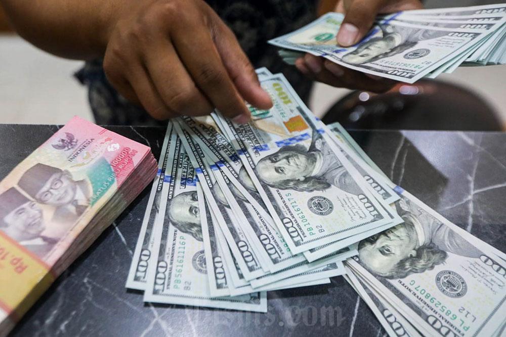 Pegawai menunjukan mata uang Dolar Amerika Serikat dan Rupiah di Money Changer, Jakarta, Senin (6/7/2026). Bisnis/Himawan L Nugraha
