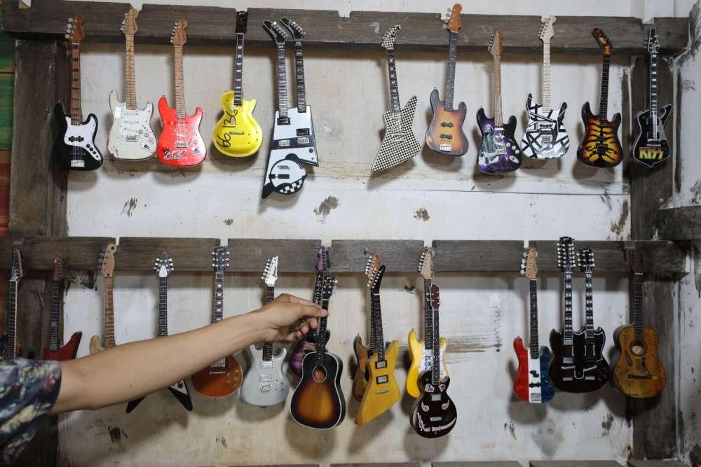 Pekerja pembuat miniatur gitar di Ngawen, Klaten sedang menata produk untuk difoto, Jawa Tengah, Kamis (3/7/2025). JIBI/Bisnis/Eusebio Chrysnamurti