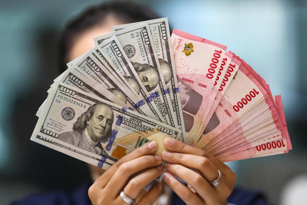 Pegawai menunjukan mata uang dolar AS dan rupiah. / Bisnis-Himawan L. Nugraha