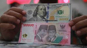 Karyawan menunjukkan mata uang rupiah dan dolar AS di tempat penukaran mata uang, Jakarta, Selasa (12/5/2026). (Bloomberg Technoz/Andrean Kristianto)