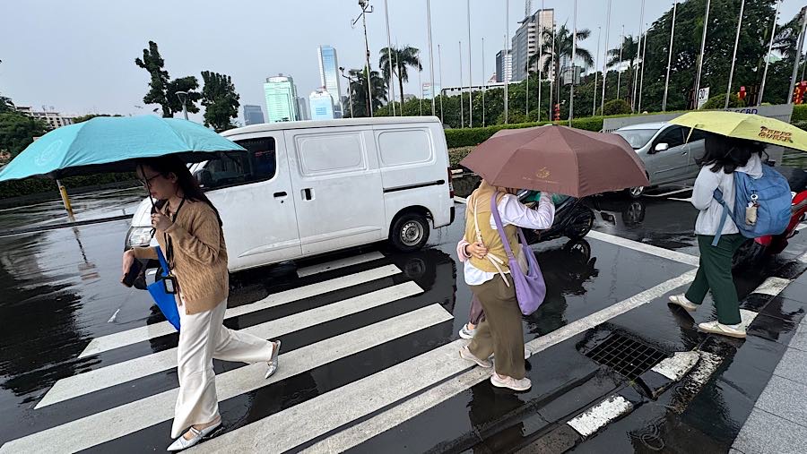 Warga menggunakan payung saat hujan di Jakarta, Kamis (29/1/2026). (Bloomberg Technoz/Andrean Kristianto)