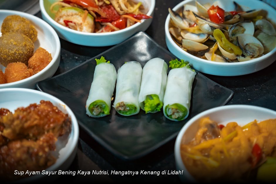 Semangkuk besar Sup Ayam Sayur Bening yang jernih, menampilkan potongan ayam, wortel oranye cerah, dan taburan daun bawang segar, terlihat sangat mengundang selera.